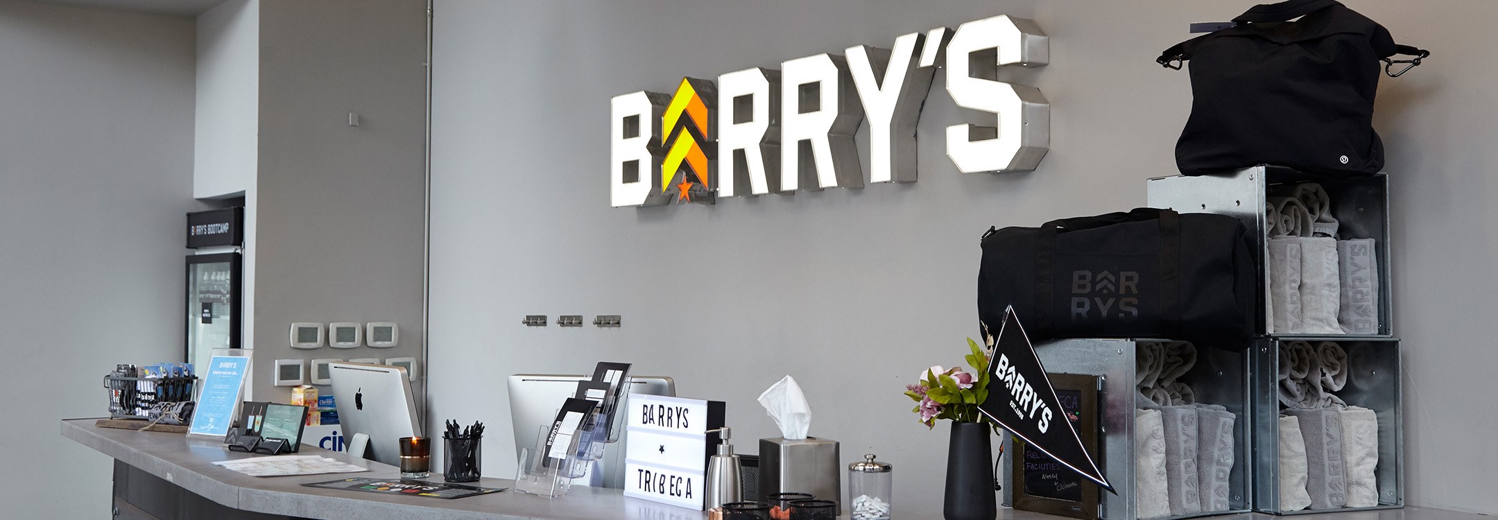 White Barry's sign with colorful logo on wall behind reception desk at Tribeca studio location