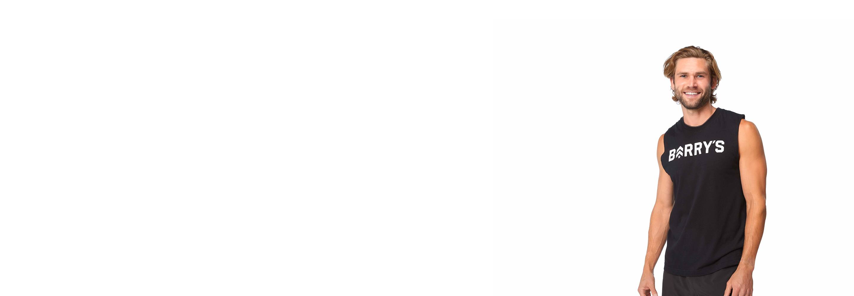 Barry’s instructor wearing a black top standing confidently smiling against a white background