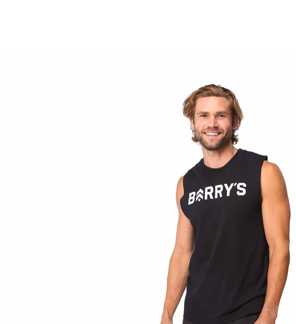 Barry’s instructor wearing a black top standing confidently smiling against a white background