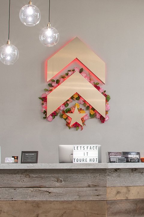 White Barry's Bootcamp upward arrows and star logo with colorful background on white wall behind reception desk at Atlanta studio location