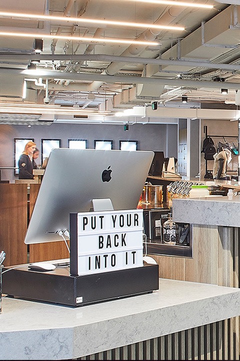 Reception desk at Barry's Bootcamp Martin Place studio with Mac computer and sign reading put your back into it