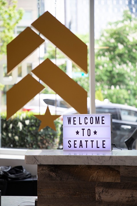 Gold Barry's Bootcamp upward arrows and start logo on glass window behind sign saying welcome to Seattle