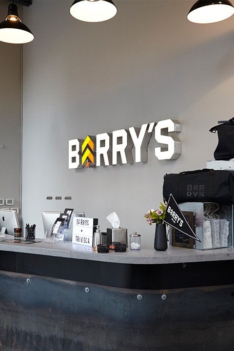 White Barry's sign with colorful logo on wall behind reception desk at Tribeca studio location