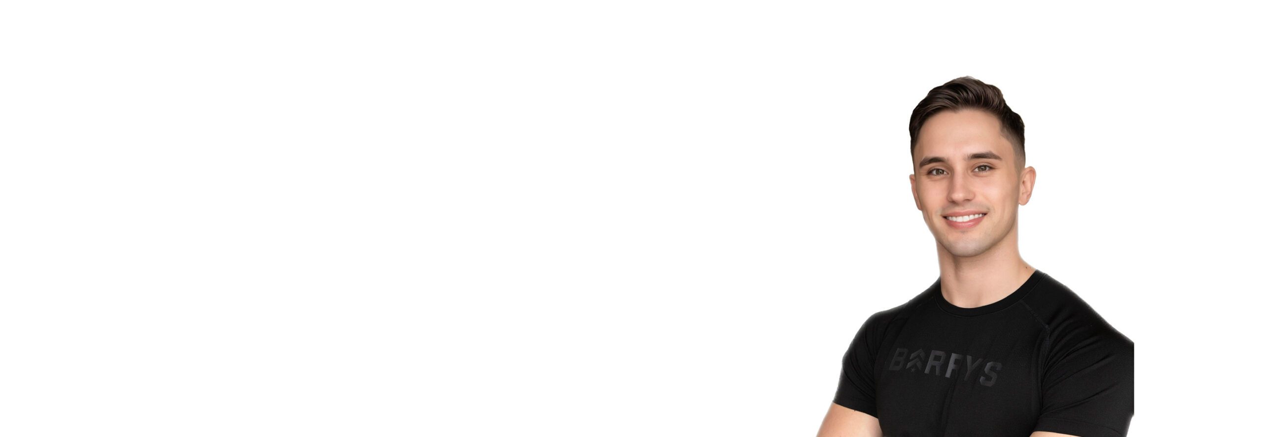 Barry’s instructor wearing a black top standing confidently smiling against a white background