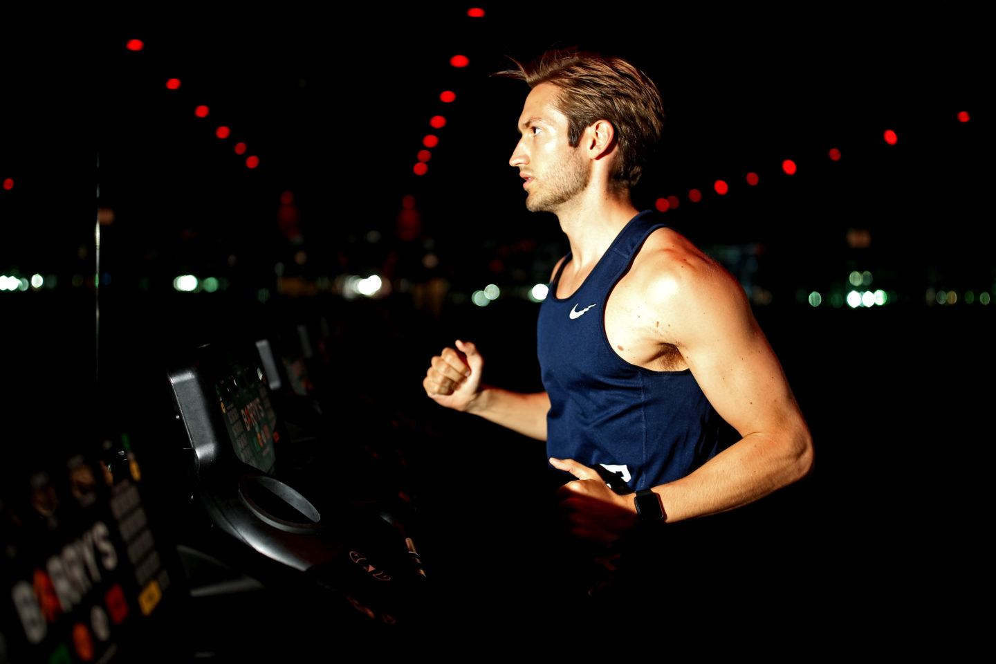Man in a navy tank top running on a treadmill