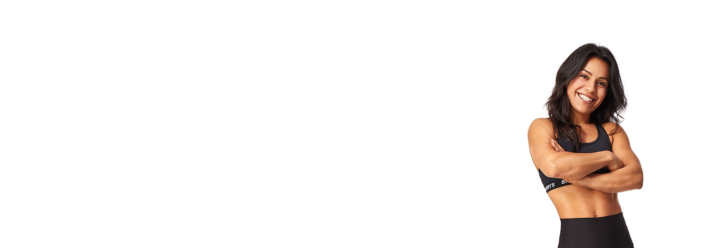 El instructor de Barry, con una camiseta negra, está de pie, sonriendo con confianza sobre un fondo blanco.