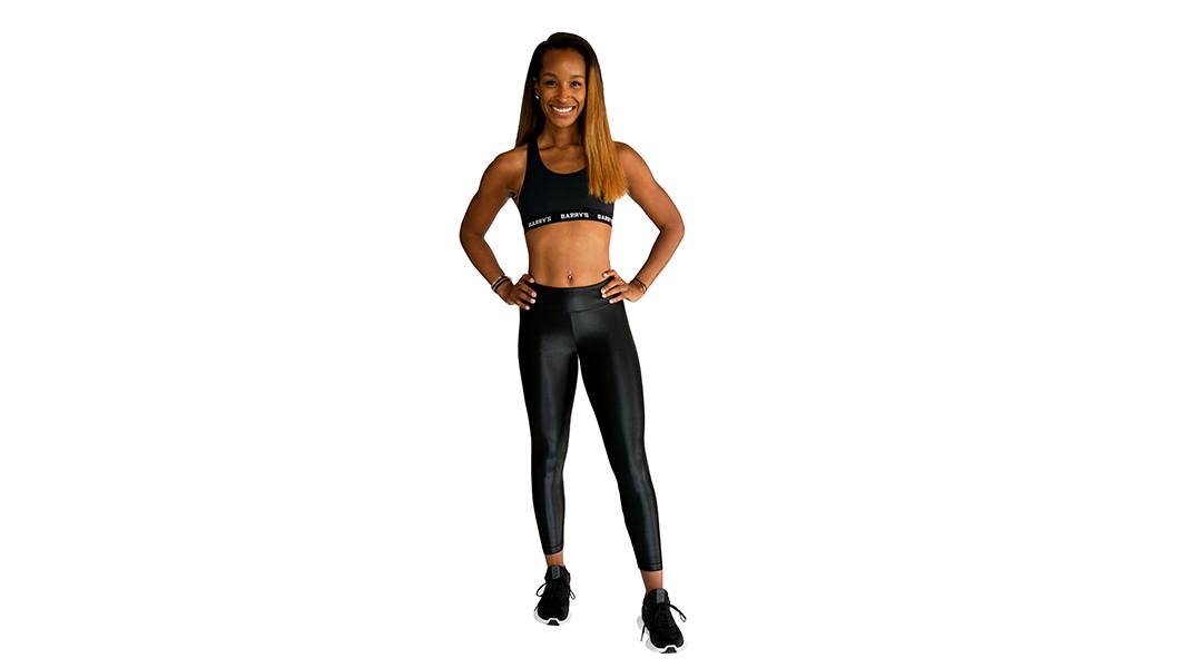 Barry’s instructor wearing a black top standing confidently smiling against a white background