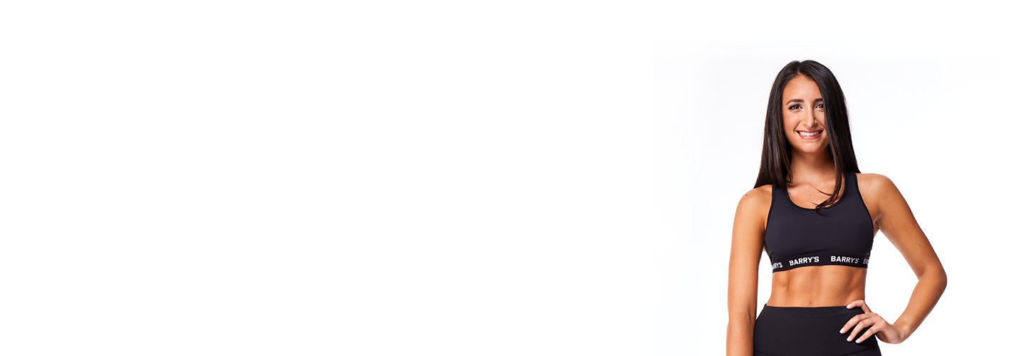 Barry’s instructor wearing a black top standing confidently smiling against a white background