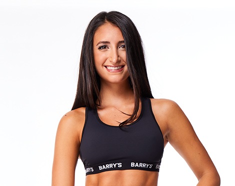 Barry’s instructor wearing a black top standing confidently smiling against a white background