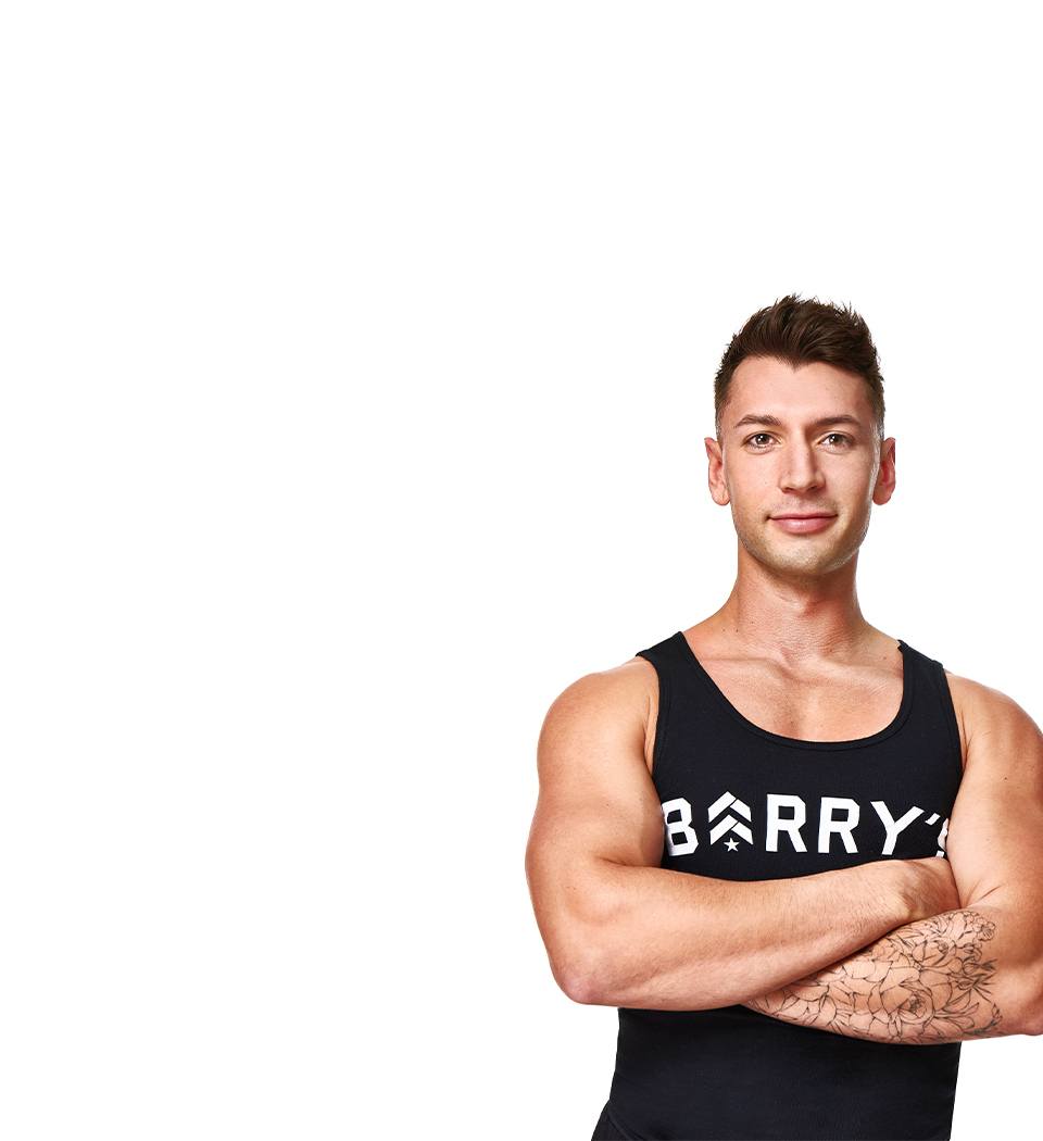 Barry’s instructor wearing a black top standing confidently smiling against a white background