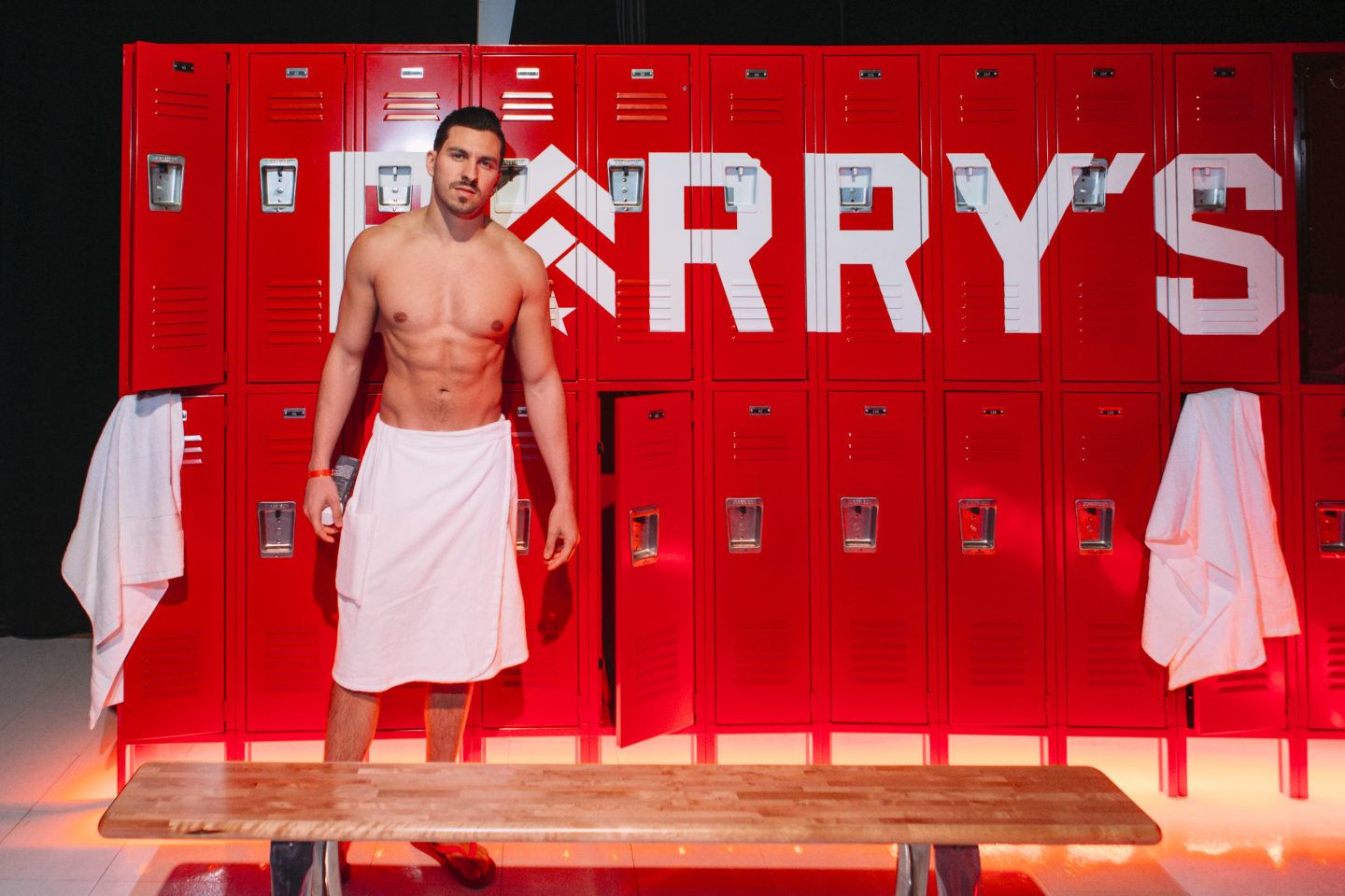 Shirtless man in a towel in front of lockers