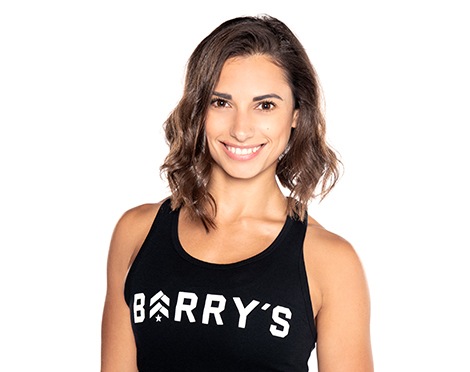 Barry’s instructor wearing a black top standing confidently smiling against a white background