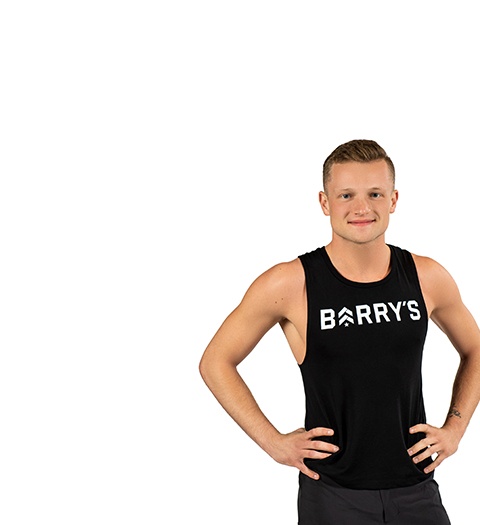 Barry’s instructor wearing a black top standing confidently smiling against a white background