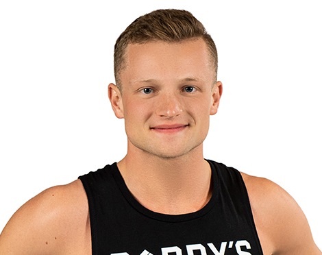 Barry’s instructor wearing a black top standing confidently smiling against a white background