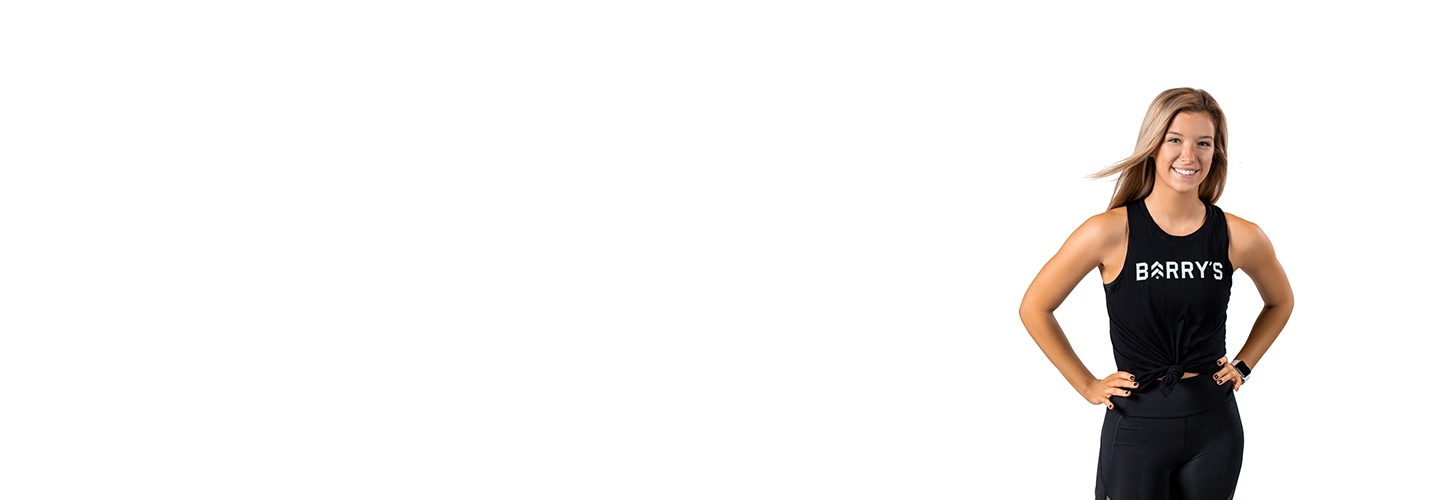 Barry’s instructor wearing a black top standing confidently smiling against a white background