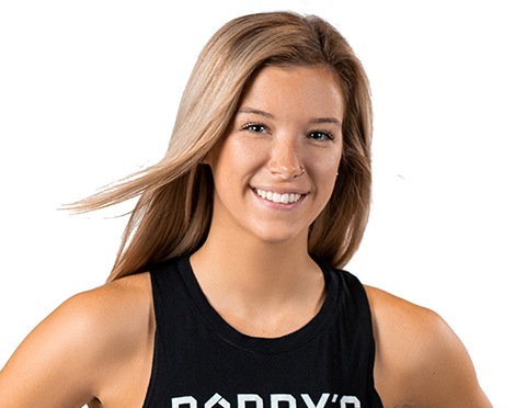 Barry’s instructor wearing a black top standing confidently smiling against a white background