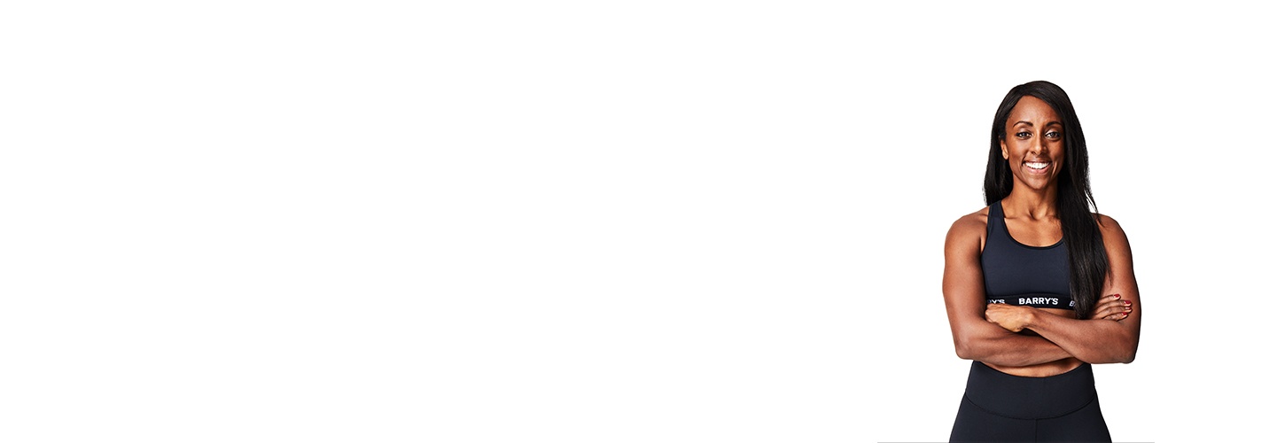 El instructor de Barry, con una camiseta negra, está de pie, sonriendo con confianza sobre un fondo blanco.