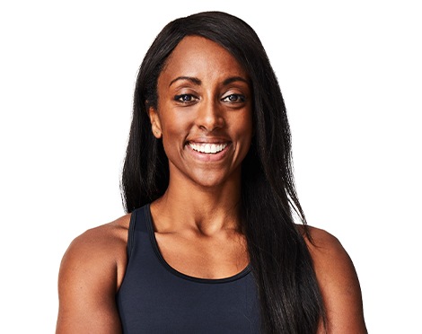 Barry’s instructor wearing a black top standing confidently smiling against a white background