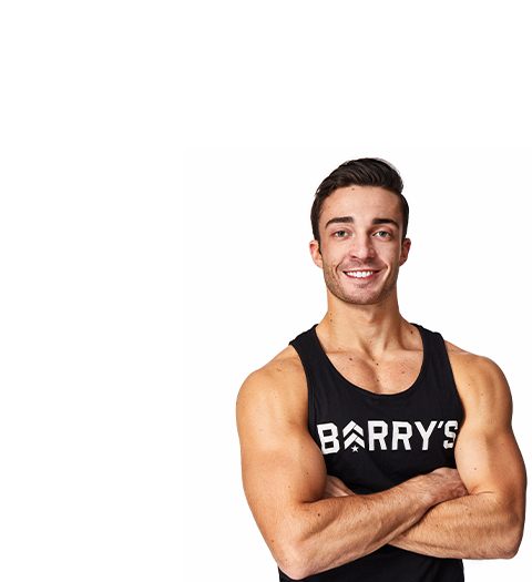 Barry’s instructor wearing a black top standing confidently smiling against a white background