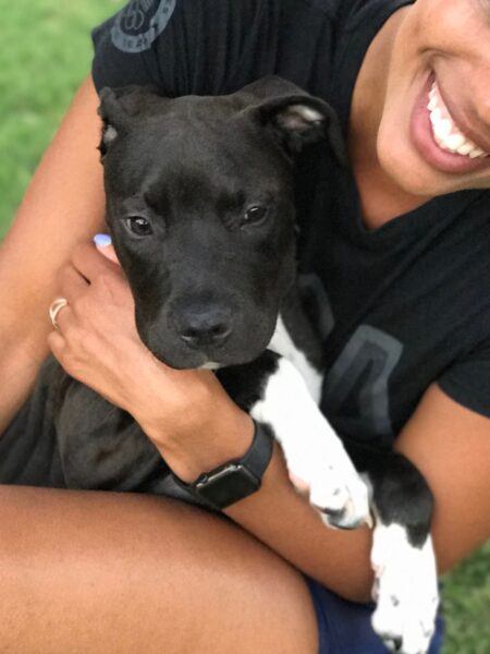 Instructrice senior, Mercedes Owens, dans l'herbe avec son chien dans les bras