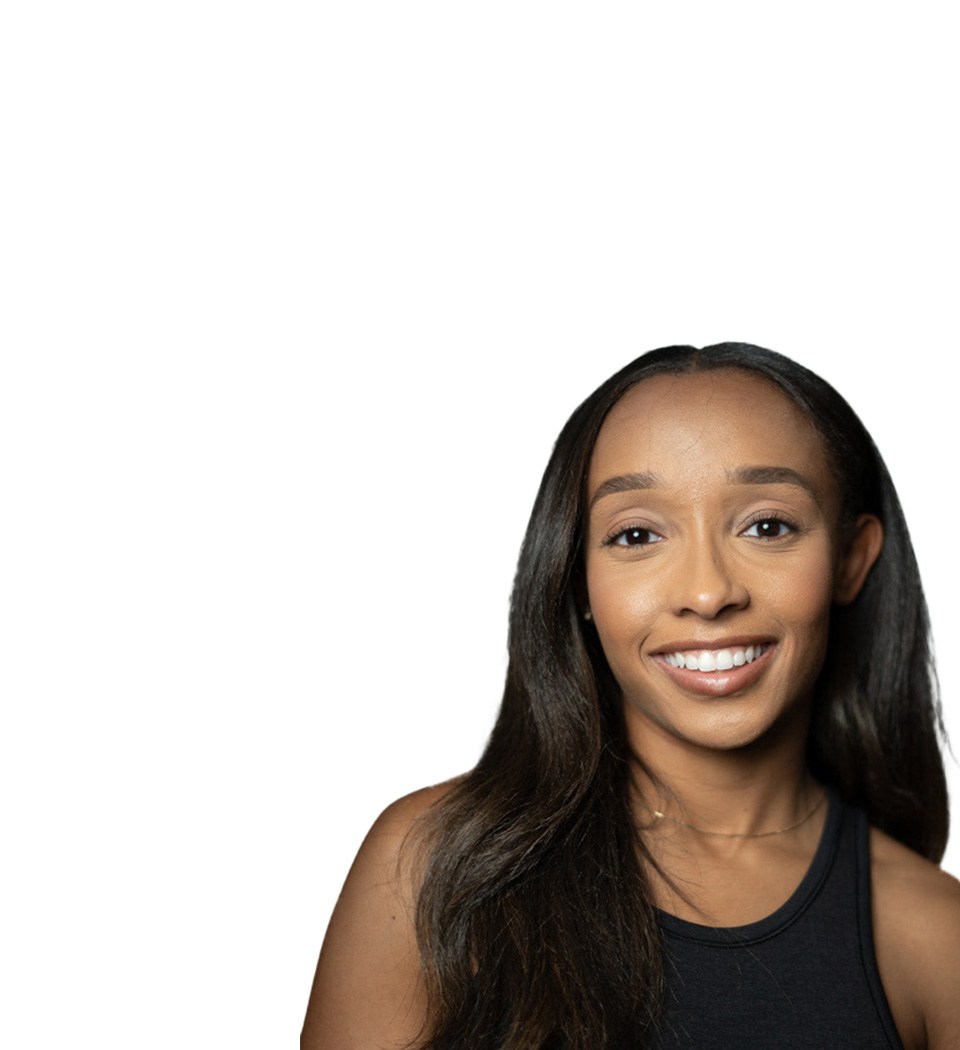 Barry’s instructor wearing a black top standing confidently smiling against a white background