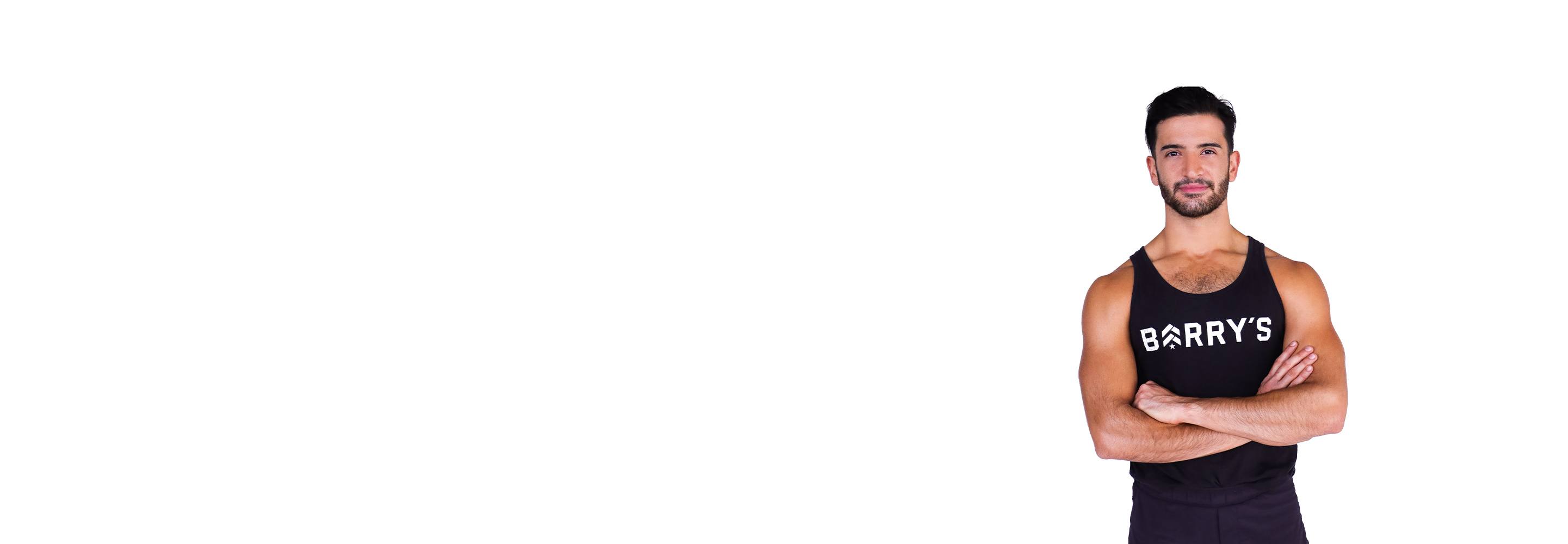 Barry’s instructor wearing a black top standing confidently smiling against a white background