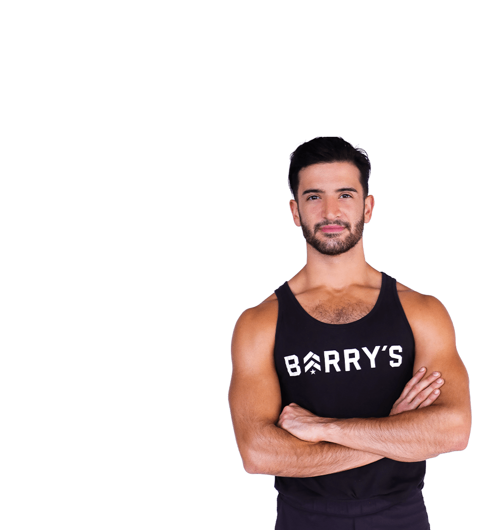 Barry’s instructor wearing a black top standing confidently smiling against a white background
