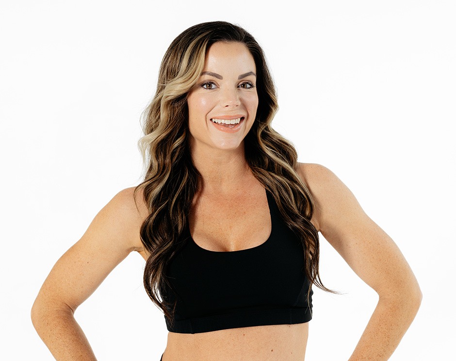 Barry’s instructor wearing a black top standing confidently smiling against a white background