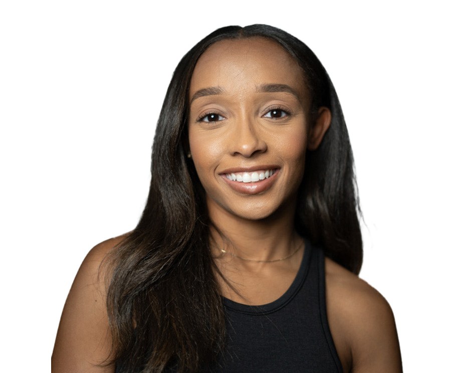 Barry’s instructor wearing a black top standing confidently smiling against a white background