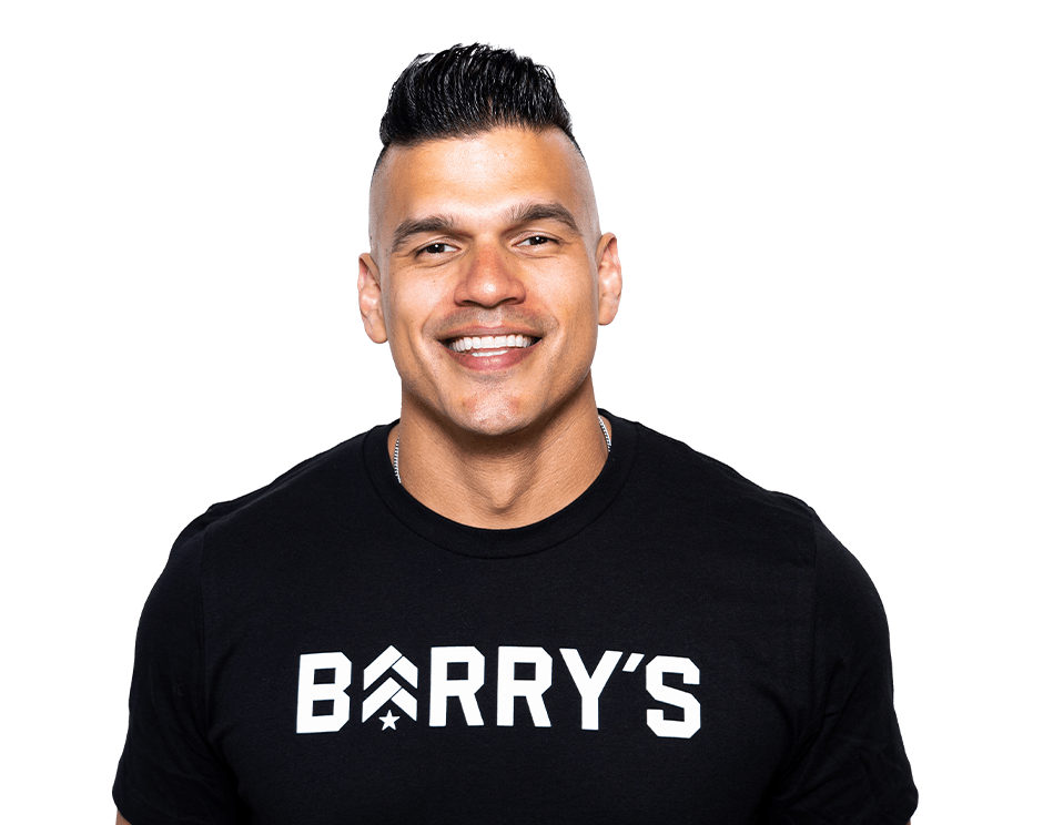 Barry’s instructor wearing a black top standing confidently smiling against a white background