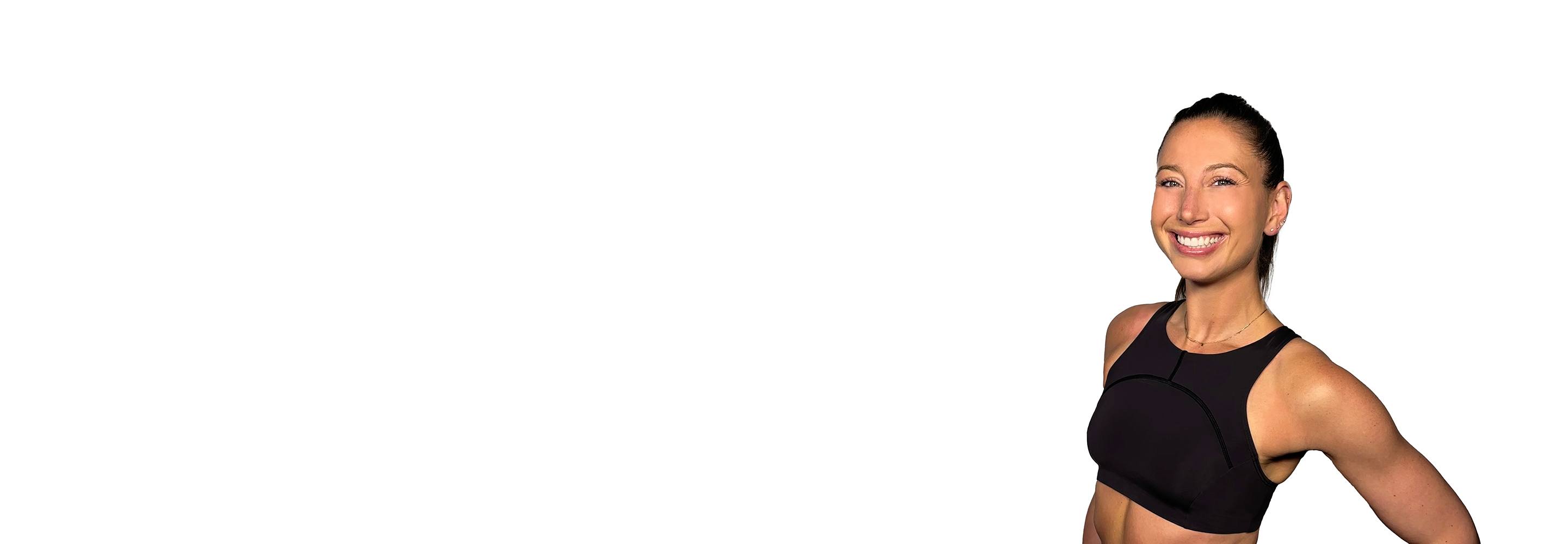 Barry’s instructor wearing a black top standing confidently smiling against a white background