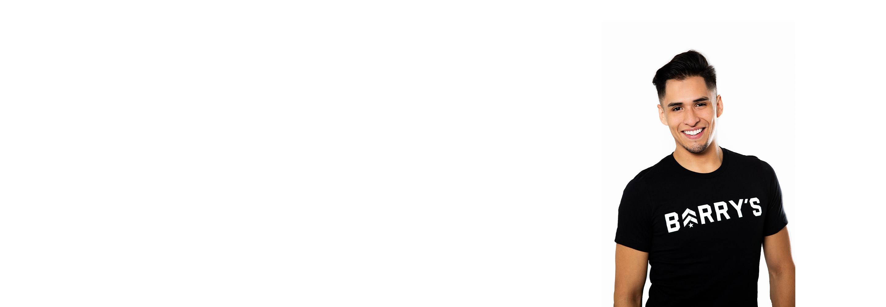 Barry’s instructor wearing a black top standing confidently smiling against a white background