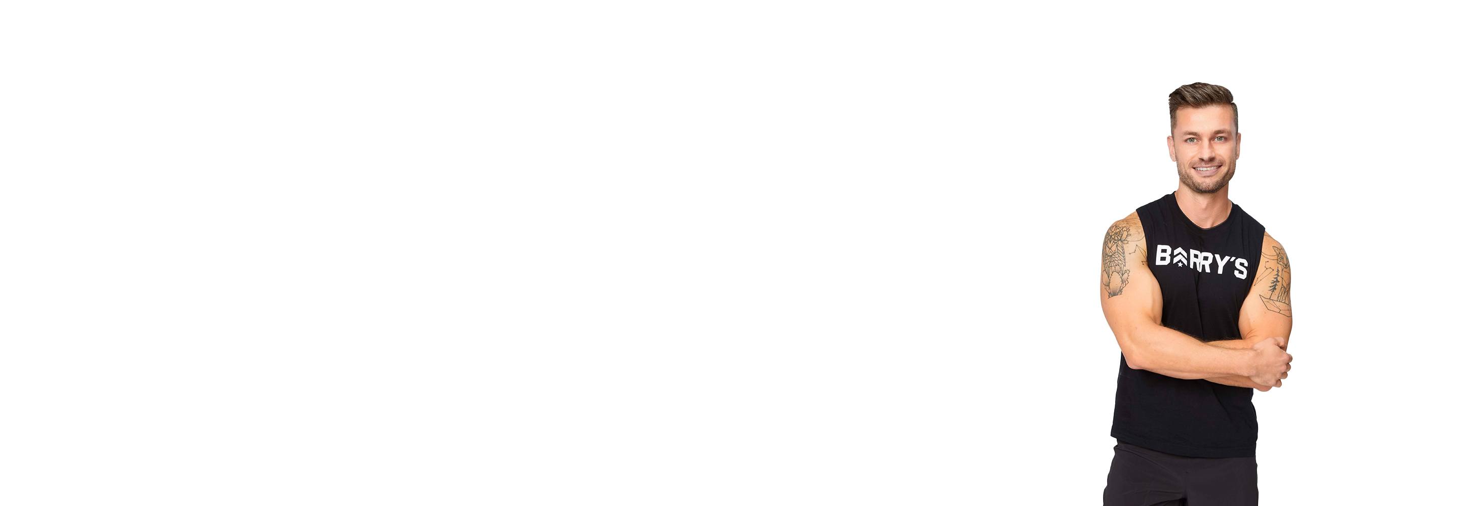 Barry's instructor standing confidently with arms crossed, wearing a black tank top against a white background, ready for the next workout challenge.