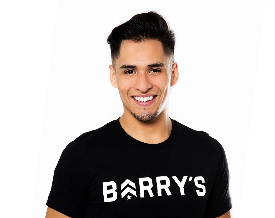 Barry’s instructor wearing a black top standing confidently smiling against a white background