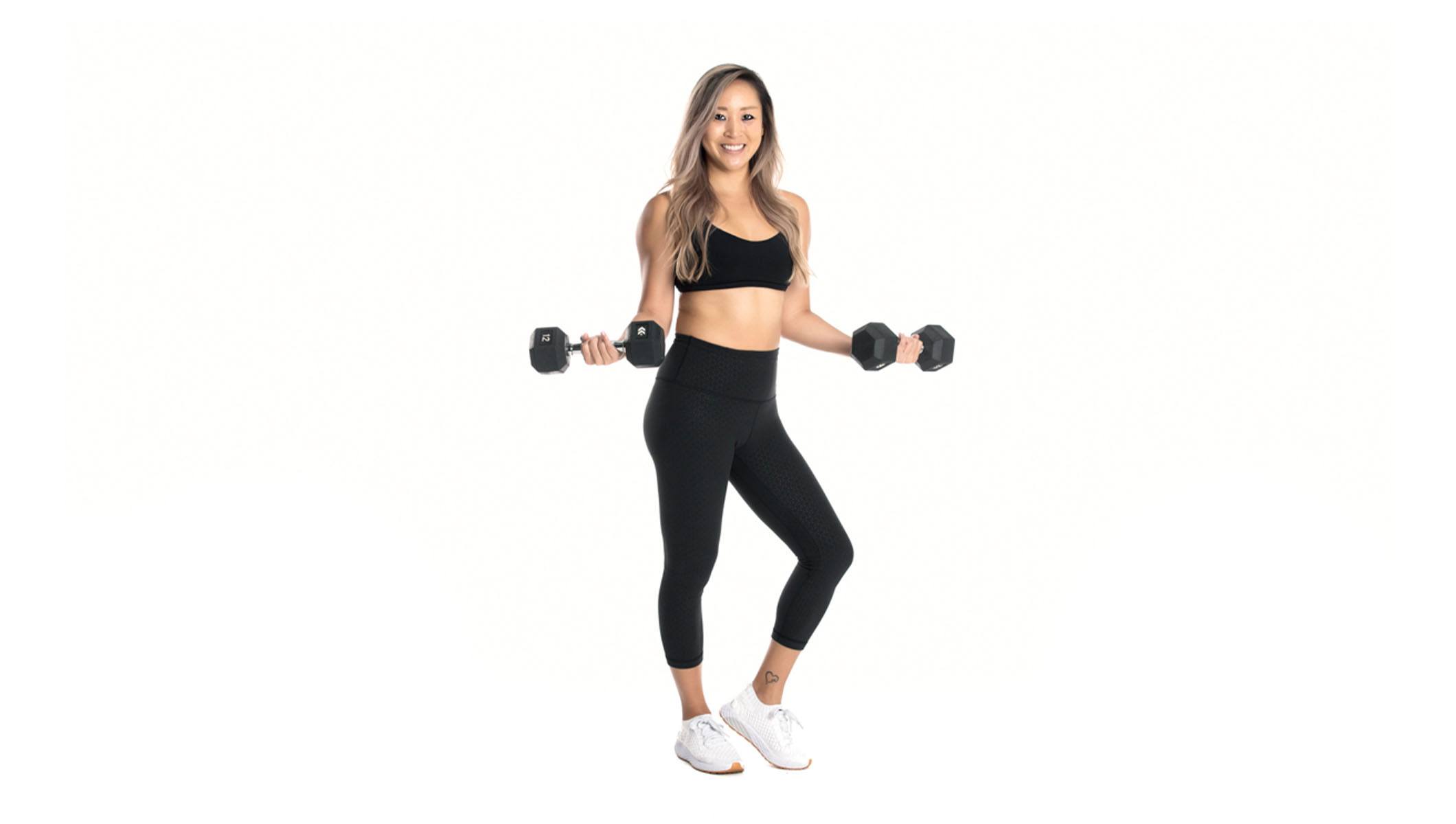 Barry's instructor standing confidently with weights wearing a black top against a white background.