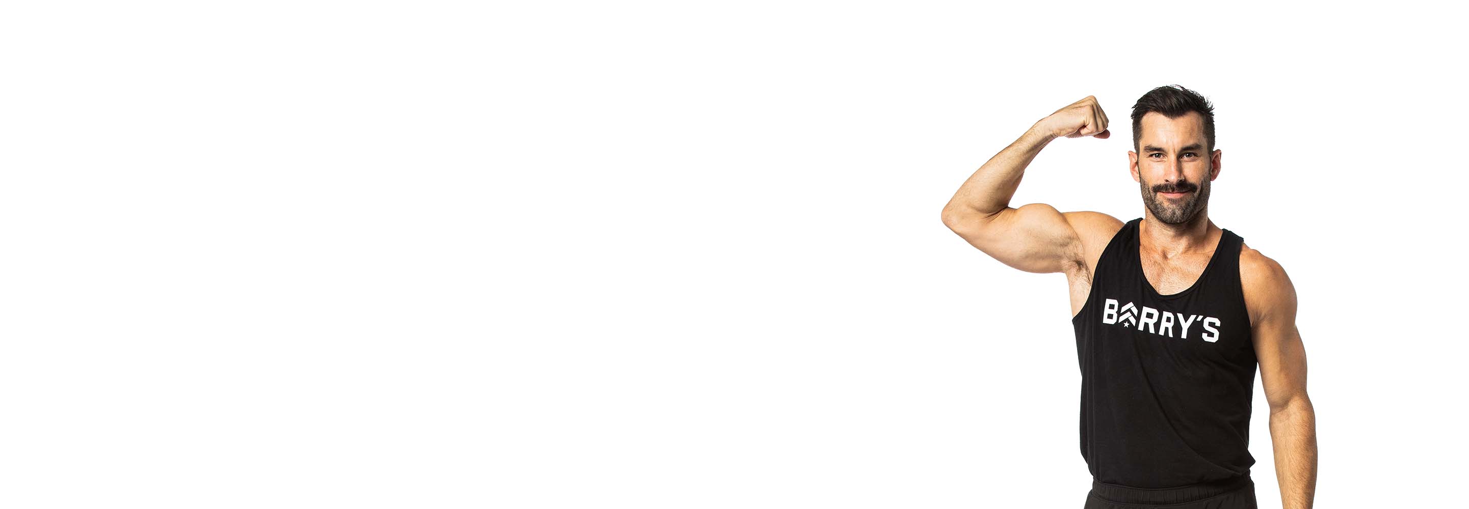 مدرب باري يرتدي قميصًا أسودًا ويستعرض عضلات ذراعه وهو يقف بثقة مبتسمًا على خلفية بيضاء