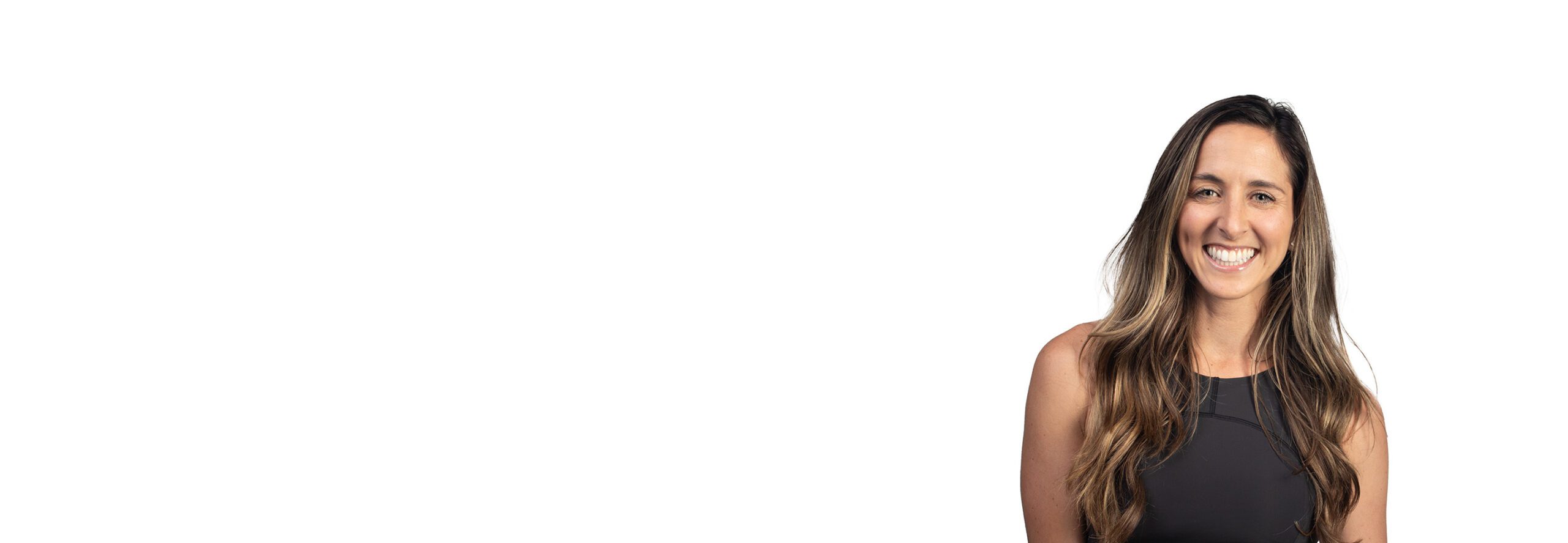 Barry’s instructor wearing a black top standing confidently smiling against a white background