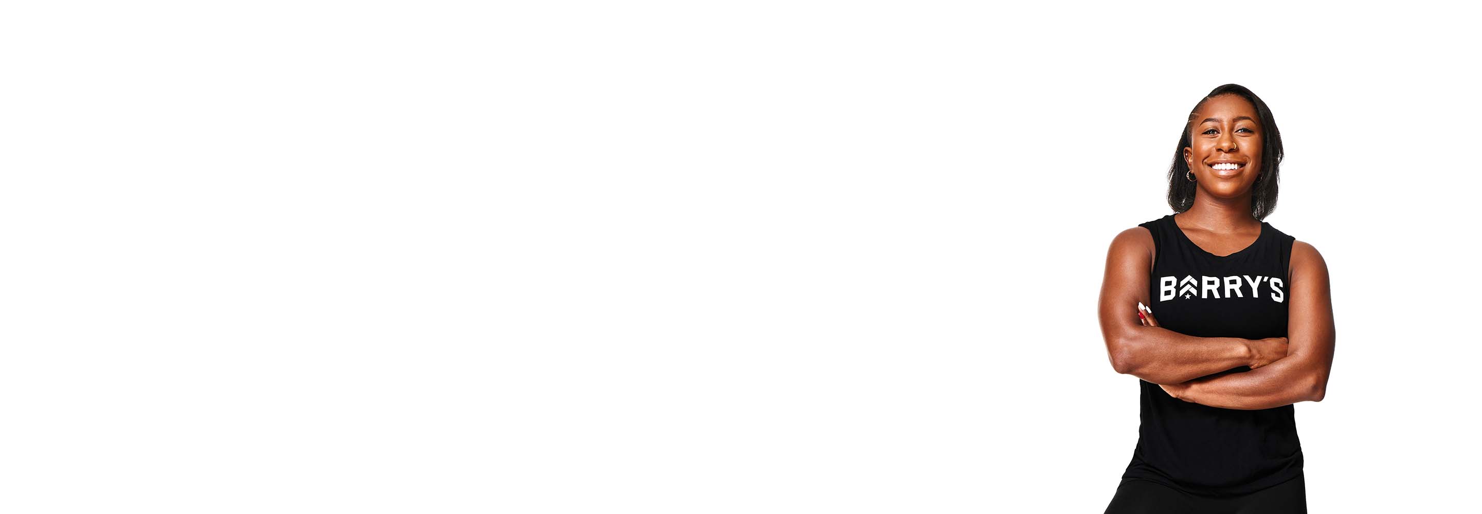 Barry’s instructor wearing a black top standing confidently smiling against a white background