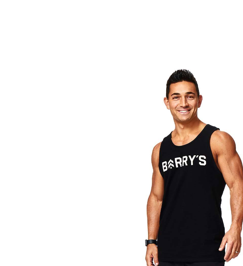Barry’s instructor wearing a black top standing confidently smiling against a white background