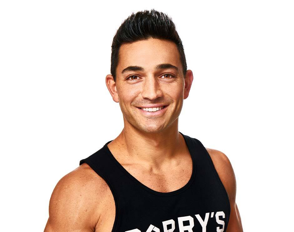 Barry’s instructor wearing a black top standing confidently smiling against a white background