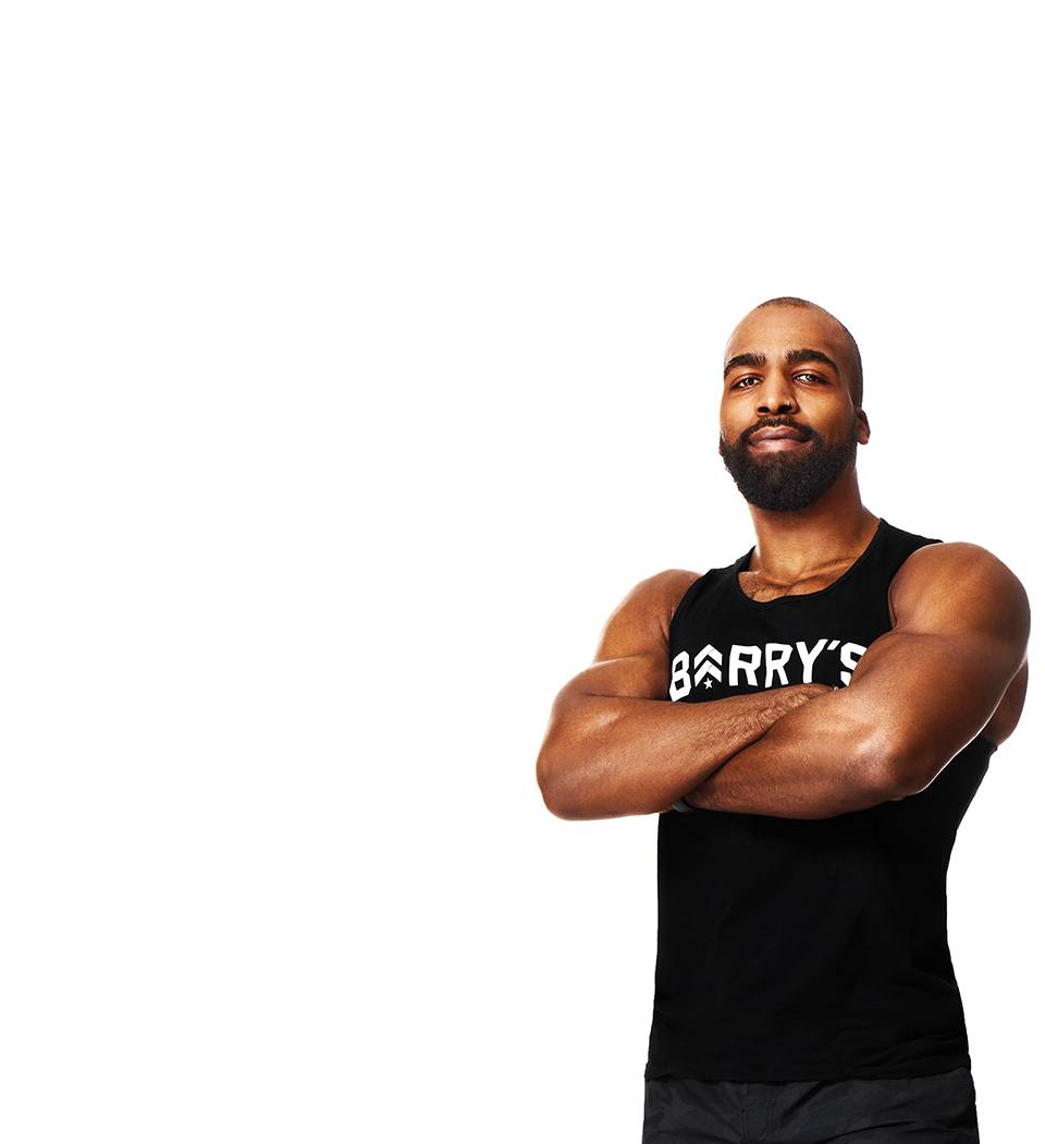 Barry’s instructor wearing a black top standing confidently smiling against a white background