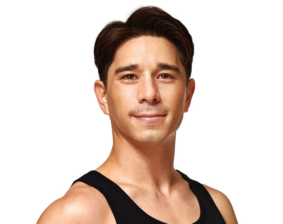 Barry’s instructor wearing a black top standing confidently smiling against a white background