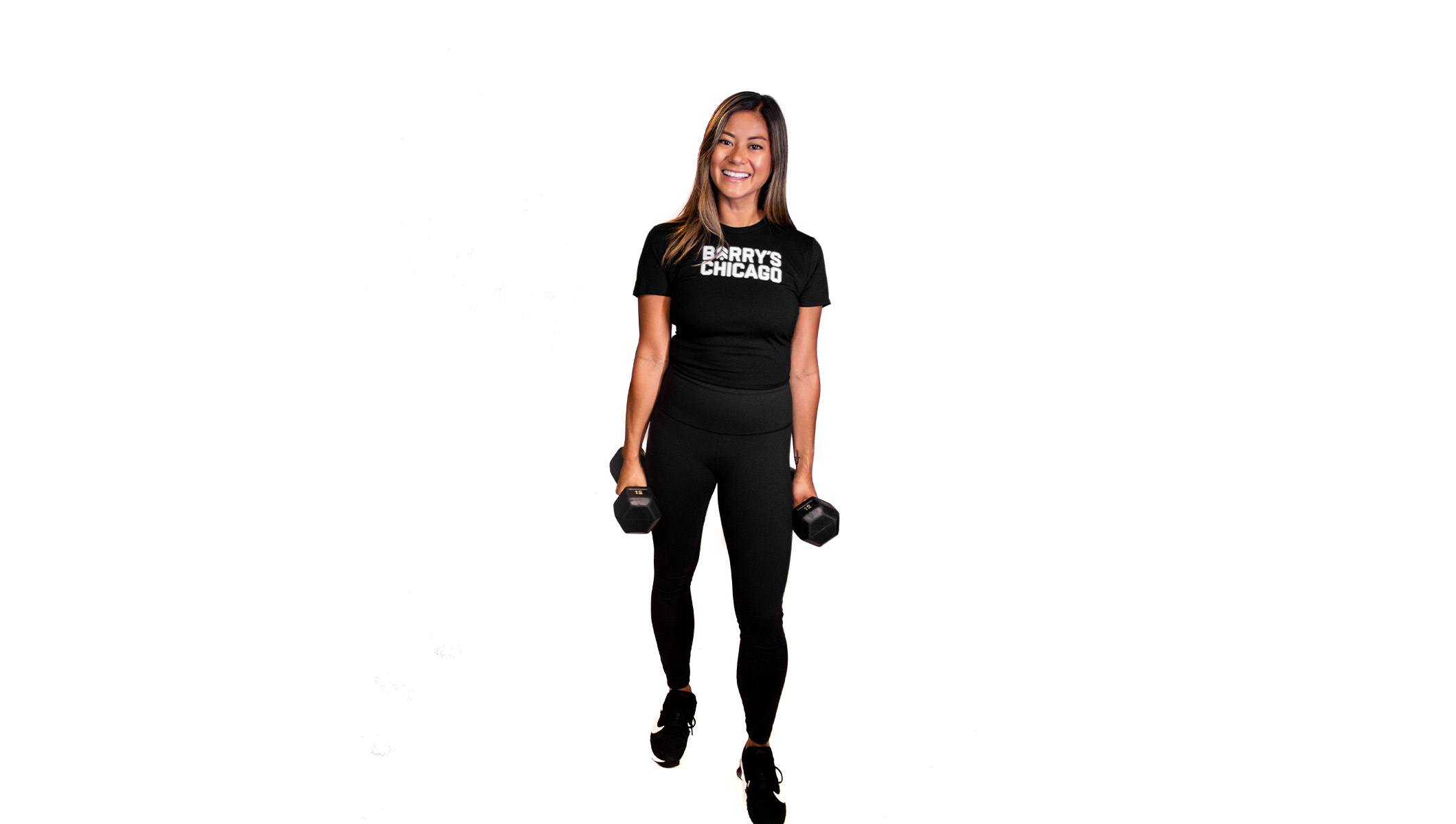 Barry's instructor standing confidently holding weights wearing a black top against a white background.
