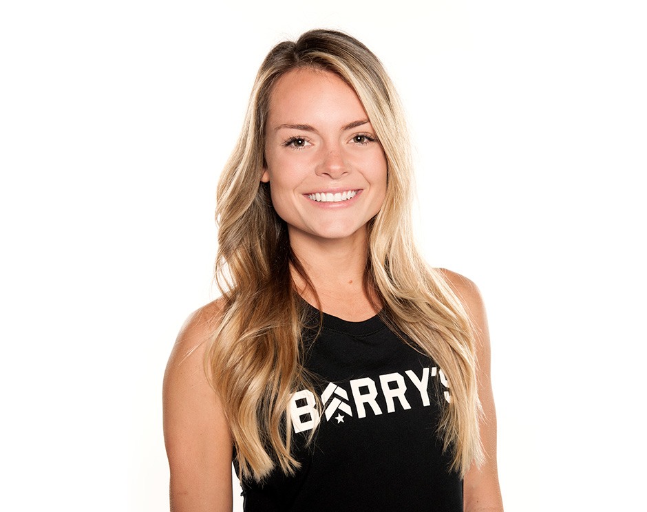 Barry’s instructor wearing a black top standing confidently smiling against a white background