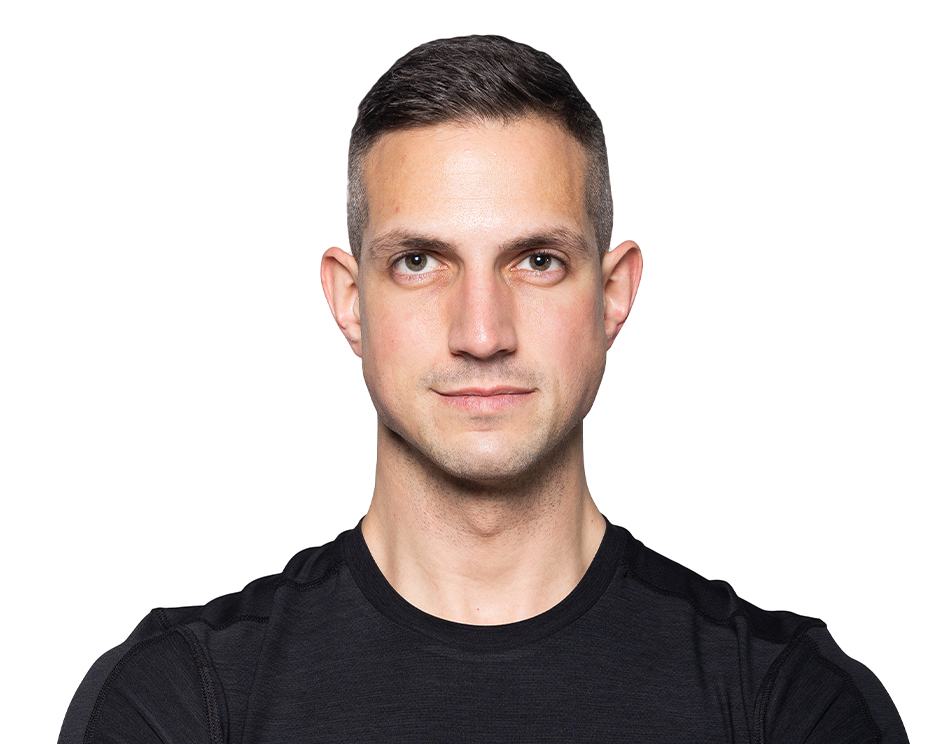Barry’s instructor wearing a black top standing confidently smiling against a white background