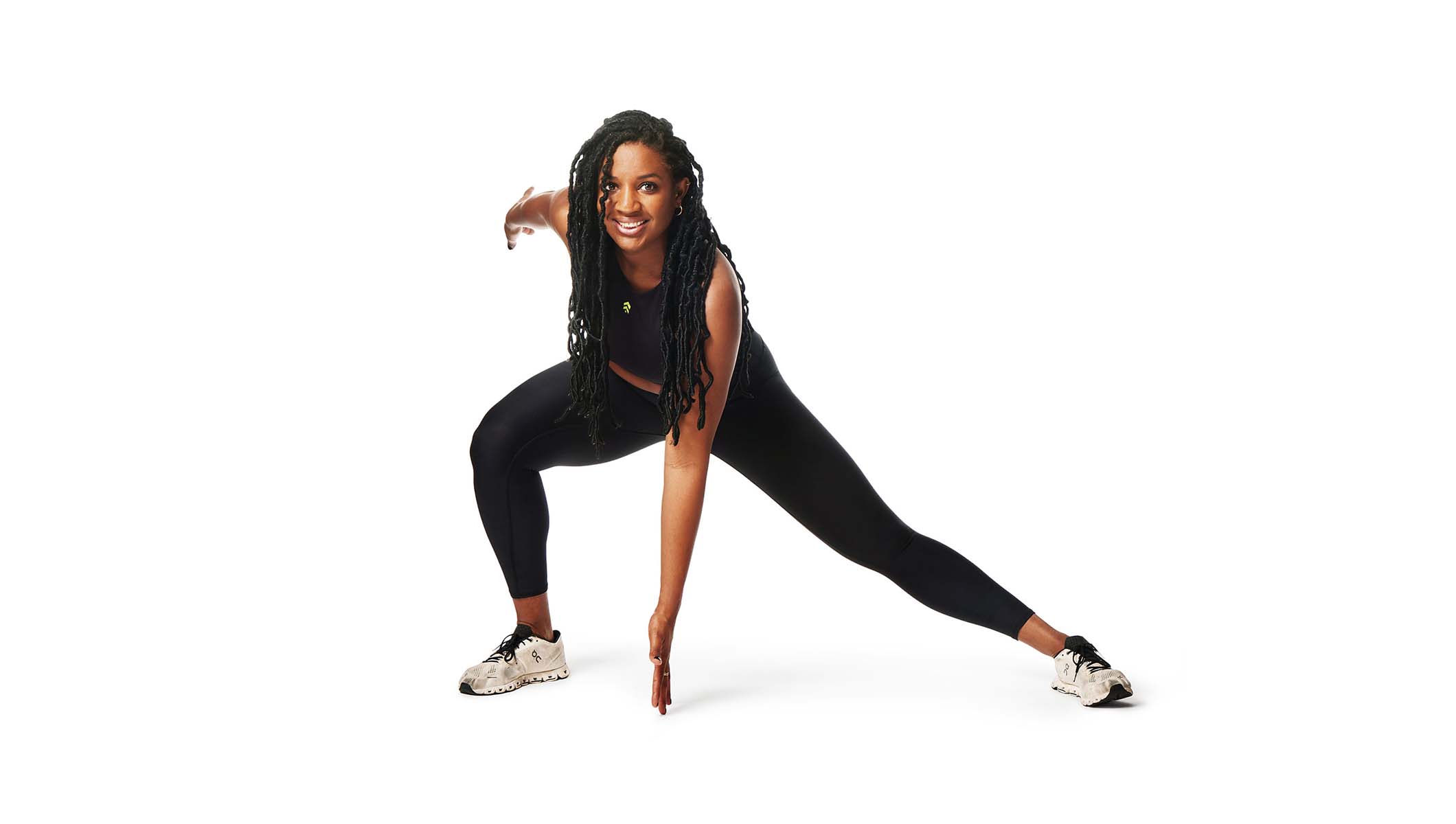 Barry’s instructor wearing a black top in a side lunge smiling against a white background