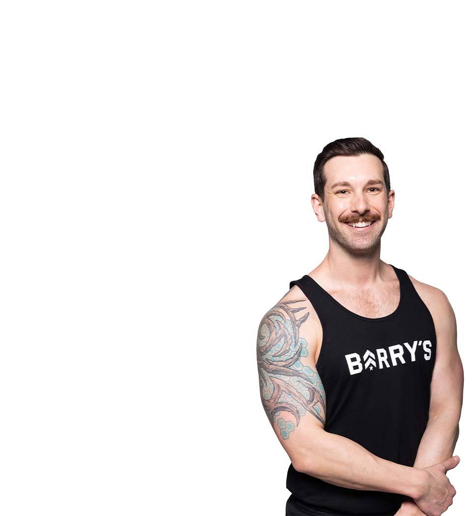 Barry’s instructor wearing a black top standing confidently smiling against a white background