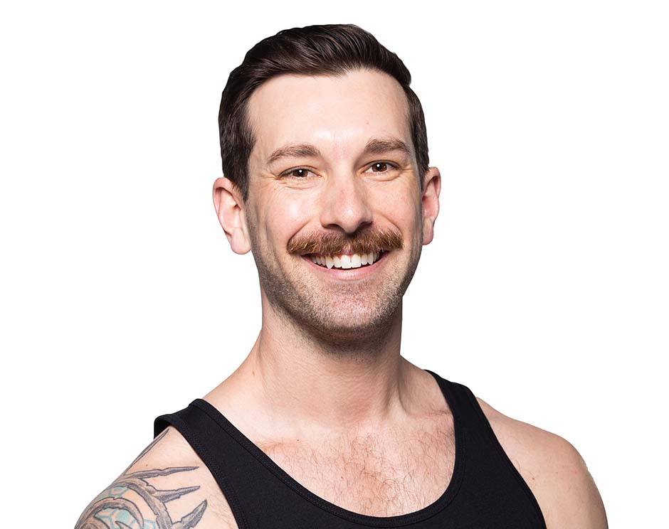Barry’s instructor wearing a black top standing confidently smiling against a white background
