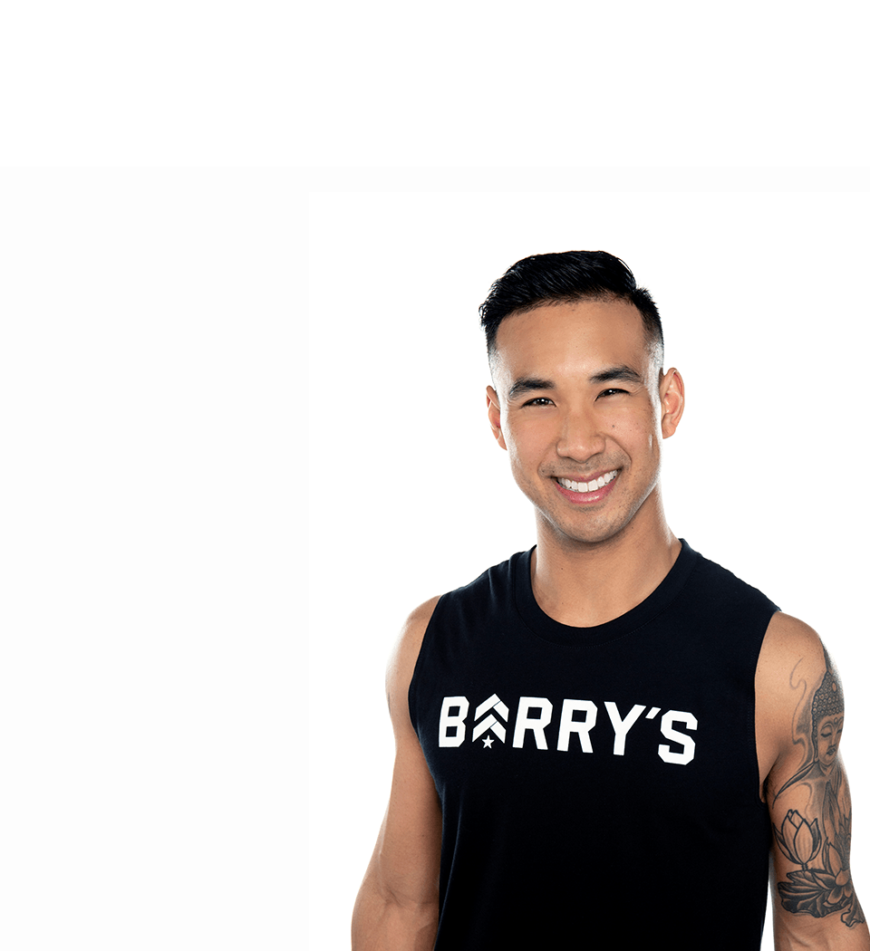 Barry's instructor standing confidently, wearing a black tank top against a white background, ready for the next workout challenge.