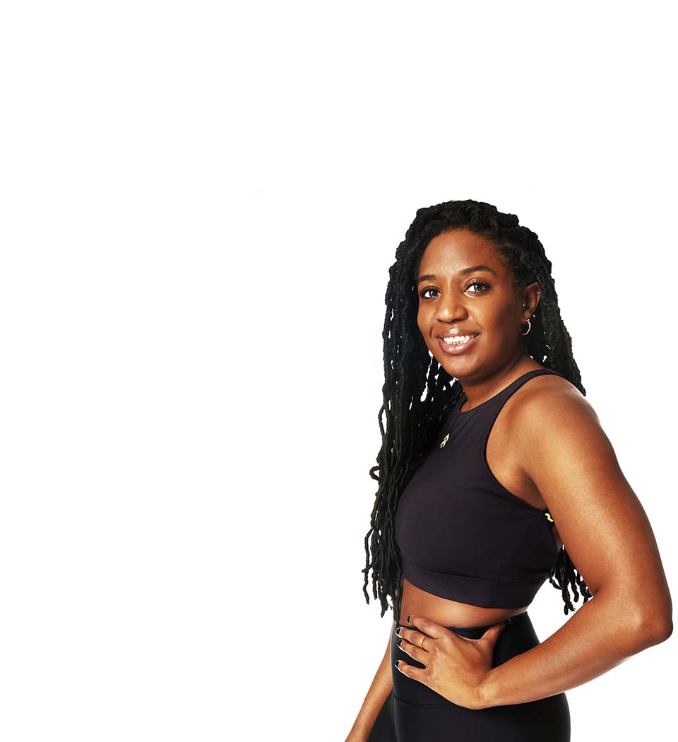 Barry’s instructor wearing a black top standing confidently smiling against a white background